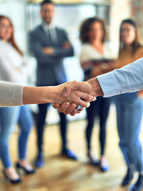 Group of business men and women standing together, shaking hands to form a partnership.