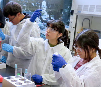 Students from a Toxic Crusaders event performing an experiment and viewing test tubes.